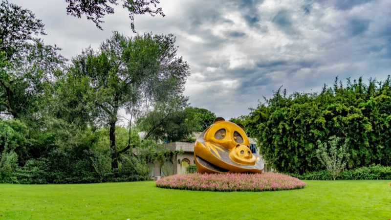 Golden panda sculpture surrounded by greenery at Chengdu Panda Base park area
