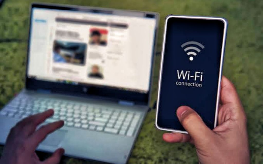 Traveler connecting a smartphone to Wi-Fi while using a laptop